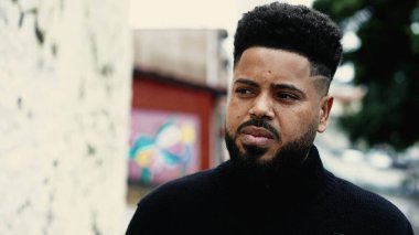 Şehir sokaklarının dışında duran, içsel, resmi bir ifadeye sahip genç bir zenci. Dalgın bir Afrikalı Amerikalının tasviri. Endişe ve endişe.