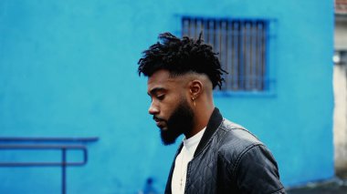 Düşünceli Afro-Amerikan genç adam, şehir sokaklarında yürüyor düşünceli ve düşünceli bir ifadeyle çevreye bakıyor. Derin iç gözlem yapan 20 'li yaşlarda biri.