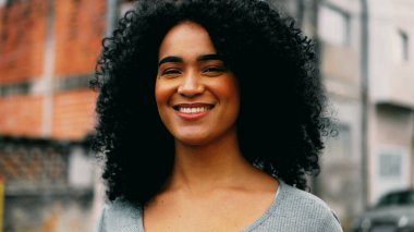 Güçlü bir Afro-Amerikalı genç kadın sokakta yürüyor, 20 'li yaşlarda kendine güvenen kıvırcık saçlı, neşeli ve mutlu bir kızın yakın çekimini izliyor.