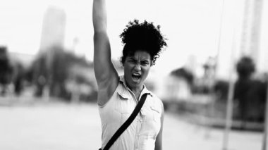 Kararlı genç siyahi bir kadın yumruğunu havaya kaldırır dramatik siyah-beyaz güçlendiğini hisseder. Afro-Amerikalı 20 'li yaşlarda kadın.