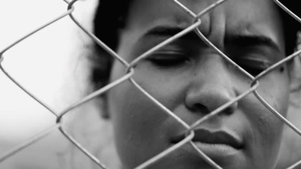 劇的な黒と白の肖像画の困難な状況で閉じ込められ 一人で感じる金属フェンスの背後に落ち込んだ若い黒人女性 — ストック動画