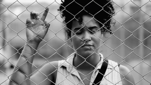 一个沮丧的年轻黑人妇女在金属栅栏后面的画像 感到被困顿和孤独 处境困难的戏剧性黑人和白人画像 — 图库视频影像