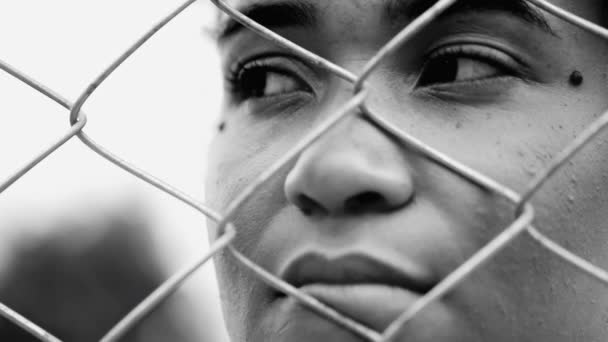 一位忧心忡忡的年轻非洲裔美国女人躲在金属栅栏后面凝视着远方 感到孤立无援 陷入了戏剧性的黑白困境 — 图库视频影像