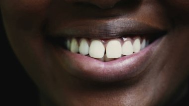 Genç siyahi bir kadının geniş sırıtışı ve yoğun beyaz vibran dişleri. Afrika kökenli yetişkin bir kız. Ağzının ve dudaklarının en ince ayrıntısına kadar gülümsüyor.