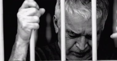 Çaresiz, yaşlı bir adam umutsuzluk içinde parmaklıklar ardında kilitli kaldı. Siyah ve beyazla boğuşuyordu. Gri saçlı, buruşuk yaşlı. Yalnızlıktan acı çekiyor. Umutsuzluk içinde ağlıyor.