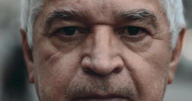 Ciddi, yaşlı bir adam makro yakın çekim gözleri. Şehir ortamında sert duygularla kameraya bakıyor. 70 'lerin erkek portresi.