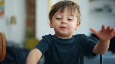 Mutfak tezgahında arka plandaki oturma odasına bakan mutlu, sevimli iki yaşındaki bir çocuk gerçek, neşeli, yakın çekim yüzü. Sarışın beyaz bir çocuğun portresi.