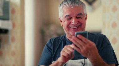 Cep telefonundan canlandırıcı mesajlar okuyan yaşlı bir adam, 70 'li yaşlarda beyaz saçlı beyaz bir erkeğin akıllı telefon ekranına bakarken onaylayıcı bir şekilde başını sallaması.