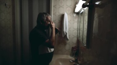 Banyo aynasının önünde yaşlı bir adam STRESS 'i hissediyor ve yaşlılığı resmeden zorlu yıllar boyunca sorunlarla boğuşuyor.