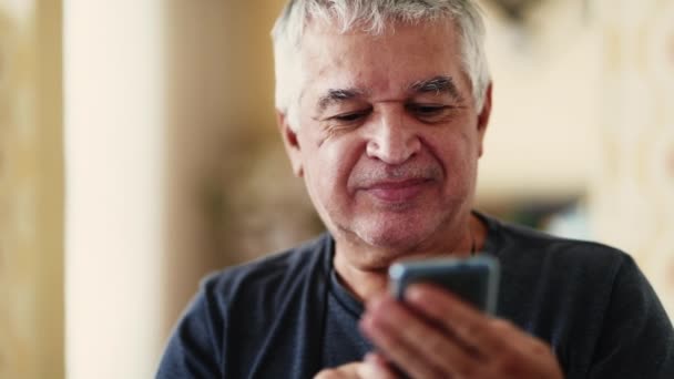 心满意足的老年白种人老人凝视着家里的手机 沉浸在现代技术之中 紧闭着脸庞 露出愉快的笑容 — 图库视频影像