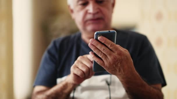 老年男子手持手机打字信息特写 70年代男性高加索人用智能手机与现代技术打交道 — 图库视频影像
