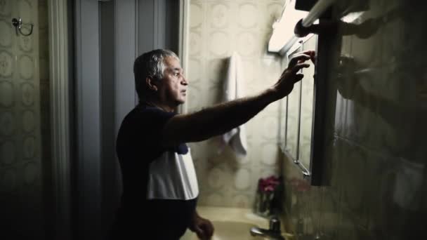 Senior Man Turns Bathroom Florescent Light Standing Front Mirror — Stock video