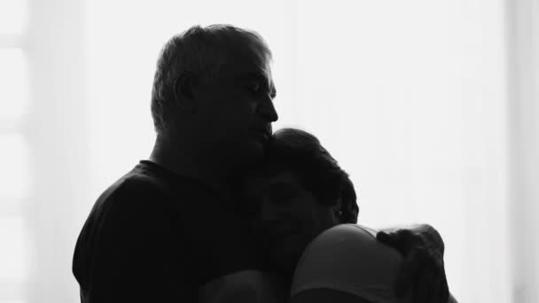 老年男子在窗边的轮廓中温柔地挽留妻子 老年时在戏剧化的黑白中照料妻子 — 图库视频影像