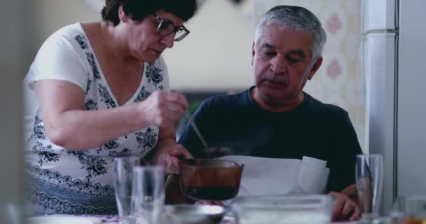 ランチタイムに夫の食事を提供するシニア配偶者 古い年齢で本物の夫と妻のライフスタイルを描く 退職年 — ストック動画