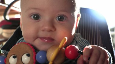 Bebek sandalyeye oturmuş oyuncakla oynuyor.