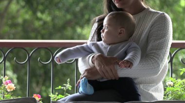 Anne kucağında bebek, oğlu pencere kenarında.