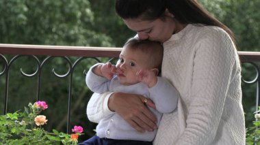 Anne şefkati ve sevgi dolu bebek bebeğini öpüyor.