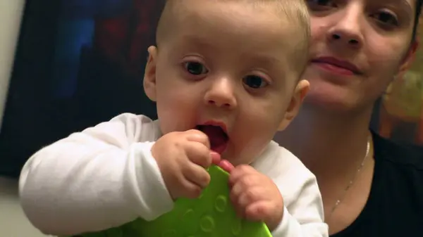 Baby putting plastic object into mouth discovering world