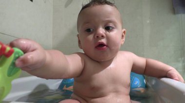 Küvetin içindeki tatlı bebek oyuncakla oynuyor.