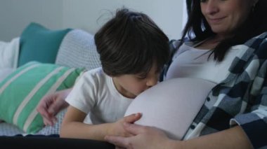 Oğlanın Doğmamış Kardeşe Sevgi Öpücüğü, Evde Kanepede Hamile Anne ile Hassas Bir Anı. Hamileliğin üçüncü üç ayı, annelik kavramı.