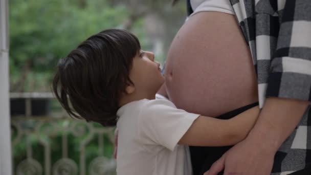 かわいい男の子は妊娠中の母親の妊娠中の腹を抱きしめ 妊娠後期に愛情と愛情を示しています — ストック動画