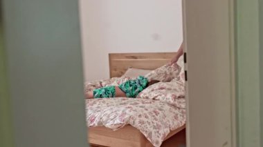 Enerjik çocuk, anne yatağını toplamaya çalışırken ebeveynin yatağında zıplayıp duruyor. Aile Haftasonu Etkinliğinin Gizli Ev Sahnesi  