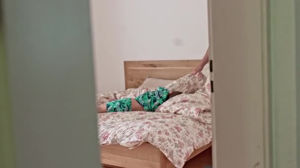 一个精力充沛的孩子在父母的床上蹦蹦跳跳 而母亲却在床上打瞌睡 家庭周末活动的家庭恶景 — 图库视频影像