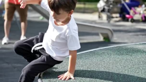 小男孩走出旋转的游乐场卡索尔 孩子在阳光下在公园玩耍 展示了平衡和敏捷性 — 图库视频影像