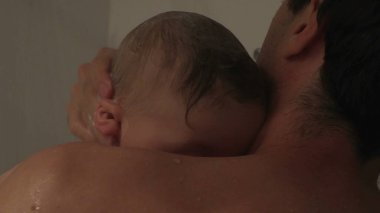 Baba, yeni yürümeye başlayan bebekle duş alıyor. Baba bebeğini yıkıyor.