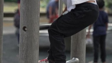 Küçük çocuk tahta ve metal platforma tırmanıyor - çocuk oyun alanında oynuyor