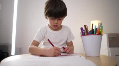 Çocuk renkli kalemle kağıda resim çiziyor. Yaratıcı sanat eserlerine kendini kaptırmış 5 yaşında bir çocuk.