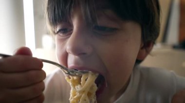 Çocuk spagetti yiyor, 5 yaşındaki çocuğun geniş yakın plan yüzü zengin karbonhidratlı makarna yiyor.