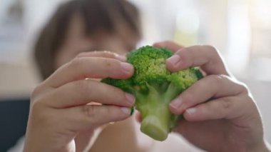 Seçici çocuk, yiyeceği parçaları brokoliden elleriyle ayırır.