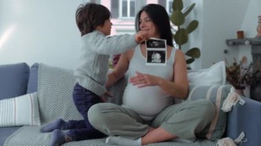Ultrason Fotoğraflı Anne ve Çocuk - 30 'lu yaşlarda bir anne ve 5 yaşında bir oğlu, 3 aylık dönemde evde koltukta poz veriyor.