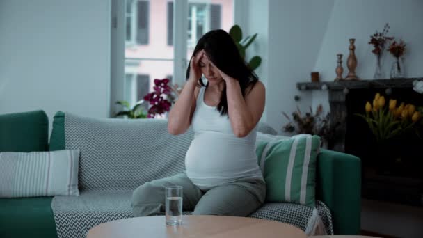 30多岁的孕妇坐在沙发上与头疼和疼痛作斗争 产妇保健概念 — 图库视频影像