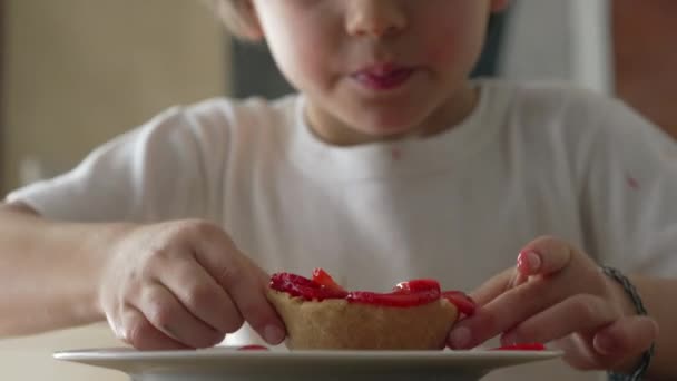 一个小男孩在吃芝士蛋糕甜点 5岁的孩子从盘子里抓食糖 — 图库视频影像