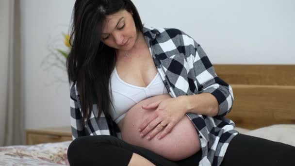 Hamile Bir Kadın Hamileliğinin Üçüncü Ayında Karnını Okşuyor Yatakta Oturuyor — Stok video