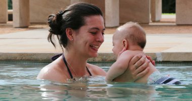 Baby newborn with mother at the swimming pool water