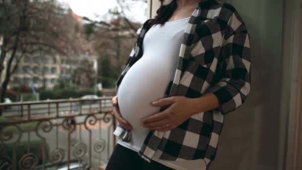临终关怀的孕妇站在公寓阳台旁温柔体贴地爱抚着肚子 从上面看去 面带微笑 母爱的概念 — 图库视频影像