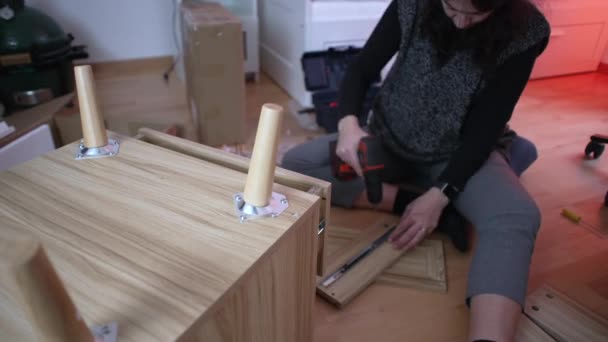 Жінка Збирає Меблі Новому Будинку Використовуючи Бурову Машину Будівництва Тумби — стокове відео