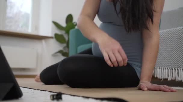 妊娠中の女性 ヨガマットに座って 自宅のリビングルームフロアで3回目の妊娠中の毎日のトレーニングルーチン中に運動する準備 瞑想する準備 — ストック動画