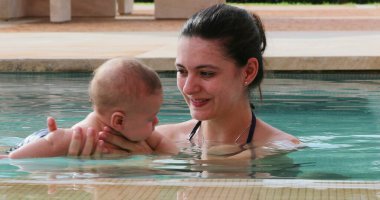 Newborn baby infant toddler boy with mother inside swimming pool