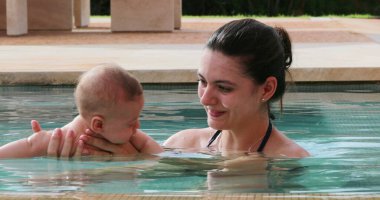 Newborn baby infant toddler boy with mother inside swimming pool