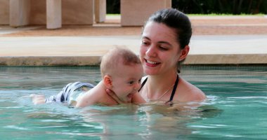 Newborn baby inside swimming pool water with mother