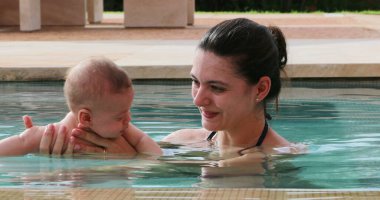 Newborn baby infant toddler boy with mother inside swimming pool