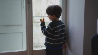 Düşüncelere dalmış küçük bir çocuğun yemek yerken pencereden dışarı bakması. düşünceli çocukluk