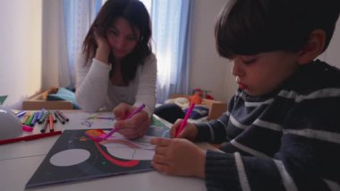 Onlar yatak odasında birlikte resim çekerken anne ve çocuk arasındaki bağ. 4 yaşındaki çocuk, anne babasıyla kağıt üzerine renkli kalemle resim çiziyor.
