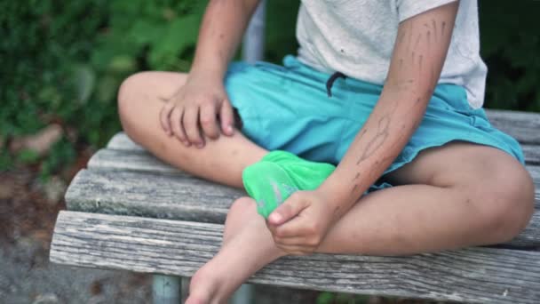男孩在公园长椅上坐下时完成袜子的调整 — 图库视频影像