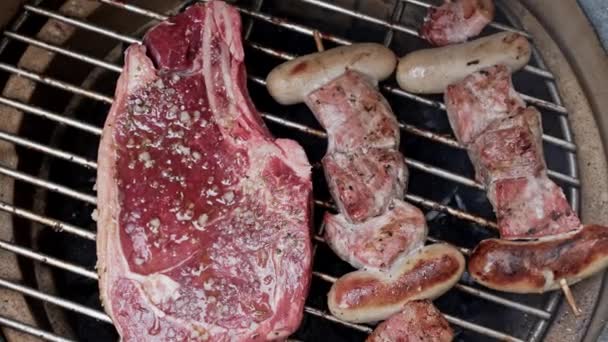 Roasting Portable Charcoal Grill Succulent Steak Alongside Pork Sausage Skewers — Stock Video