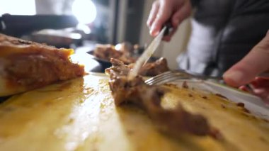 Yakın plan insan yemek hazırlar, çatal ve büyük bıçakla et keser, yemek pişirir.
